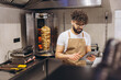 © anatoliycherkas - Arab man chef managing online orders on tablet in fast food restaurant kitchen with shawarma cooking