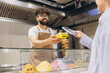 © anatoliycherkas - Arab chef receiving smartphone payment from a customer, smiling in a shawarma shop, offering contactless checkout