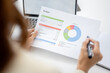 © BTM_Graphic - Close up of professional businesswoman analyzing financial report with charts and graphs on paper at office desk.