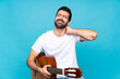 © luismolinero - Young man with guitar over isolated blue background with neckache