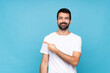 © luismolinero - Young man with beard  over isolated blue background pointing to the side to present a product