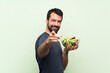 © luismolinero - Young handsome man with salad over isolated green wall points finger at you with a confident expression