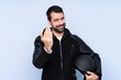 © luismolinero - Man with a motorcycle helmet over isolated background inviting to come with hand. Happy that you came