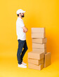 © luismolinero - Full-length shot of delivery man among boxes over isolated yellow background in lateral position