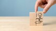 © Karla - Hand is placing a wooden block featuring a light bulb icon, symbolizing a new idea, on top of another block with a helping hand icon.