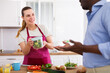 © caftor - Smiling young wife giving container with salad to husband leaving for work