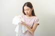 © KMPZZZ - Housewife, asian young maid woman hand in holding white T-shirt, looking at cloth stain, spot dirty or smudge on clothes, dirt stains for cleaning before washing, making household working at home.