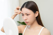 © KMPZZZ - Anti aging, worry puberty asian young woman, stressed girl looking in mirror, allergy presenting an allergic reaction from cosmetic on face. Beauty, health care from acne problem, dry skin, treatment.
