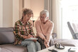 © luciano - Smiling Senior woman and Caregiver Sharing a Moment sitting together on sofa at home. Concept of assistance and help to our elderly