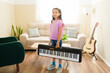 © AntonioDiaz - Full length view of a girl carrying a keyboard at home, learning to play music, developing artistic talent and creativity