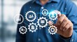 © MSTKHADIJA - Businessman interacting with a glowing digital interface of connected gears representing business process automation data flow and system synchronization for corporate strategy