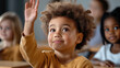 © syhin_stas - Young African American schoolboy sits at a desk, smiling and raising his hand eagerly in class, attentive and engaged in learning and classroom participation