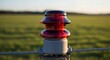 © SashaMagic - Close-up of red warning light on fence post in countryside field