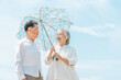 © buritora - An elderly couple, a married couple, a man and a woman using parasols under a blue sky (for protection against UV rays and heatstroke).