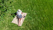 © Iuliia Sokolovska - Woman with laptop and headphones relaxing and working in a park, digital nomad girl working outdoors on summer, student studying in park, aerial drone view