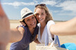 © auremar - two girl friends taking a selfie portrait on the beach