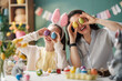 © Konstantin Yuganov - Happy Family Celebrating Easter at Home with Colorful Eggs and Bunny Ears