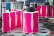 © Aleksandr Matveev - Pink adhesive labels roll on automated machinery. Labels gleam with bright magenta and white stripes. Production line moves labels with precision