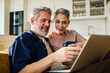 © Geber86 - Smiling senior couple using laptop at home