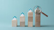 © photo for everything - Real Estate Market Analysis with Increasing House Models on Wooden Blocks and Magnifying Glass on a Serene Blue Background