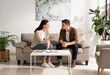 © Patrick - Young adult couple talking seriously on sofa in bright living room, relationship communication and conflict resolution at home with notes on coffee table
