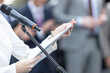 © wellphoto - Businesswoman delivering speech at microphone, reading notes during corporate conference or seminar presentation with blurred audience background
