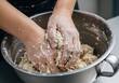 © Mst Muslima - Person mixing dough in large metal bowl with hands covered in flour