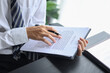 © Supitnan - Male executive singing legal documents for a corporate partnership at desk.