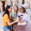 © Xavier Lorenzo - Happy female friends toasting red wine together outdoors. Young women celebrating friendship at a cafe in Italy. Lifestyle and travel concept.