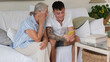© luciano - A 70-year-old woman and a young 20-year-old grandson look at the boy's cell phone together while sitting on the couch at home. Friendship and affection in a multigenerational family