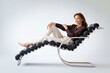 © sepy - Full length of a brunette haired woman relaxing in a modern chair against isolated background