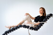 © sepy - Full length of a brunette haired woman relaxing in a modern chair against isolated background