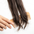 © Stella - Woman combing brown hair with wooden comb in bright lighting