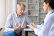 © Anastasiya - Senior male patient explaining symptoms to female doctor during clinic consultation. Healthcare professional taking notes and assessing medical condition