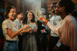 © Zamrznuti tonovi - Diverse group of young people cheering and smiling, making a toast with sparkling wine at a celebration party