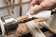 © Stitch - Woodturner applying polish with a paper towel to a shiny wood and resin pen blank on a lathe