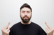 © Timur Abasov - A portrait of an expressive man with a beard showing the middle finger gesture against a white studio background. Stock photo