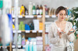 © JackF - Pleased young woman deciding which makeup items to buy in retail store