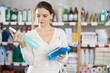 © JackF - Young woman buyer chooses cleaning spray in household chemicals store