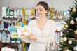 © JackF - Young female shopper buying gift set of care products in household chemicals store decorated for christmas