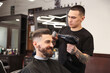 © New Africa - Stylist blow drying man's hair in barbershop