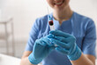 © New Africa - Nurse holding syringe with blood sample in clinic, closeup. Space for text