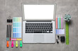 © Pixel-Shot - Laptop with earphones, stationery and color palettes on grunge grey background, top view