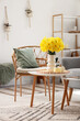 © Pixel-Shot - Interior of living room with armchair, coffee table and vase of narcissus flowers