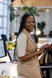 © Wavebreak Media - African American woman in her 20s holding smartphone wearing blazer in office with data monitors
