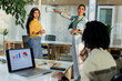 © Wavebreak Media - Diverse coworkers collaborating on glass whiteboard in office with laptop charts, copy space