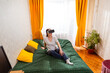 © _KUBE_ - Woman interacting with virtual reality spaces while sitting on bed, embracing the evolution of digital entertainment. Wide shot, top view