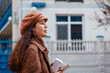 © _KUBE_ - Side view of young woman in a beret and coat is walking around the city with coffee. City leisure