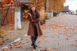 © _KUBE_ - A young Caucasian woman in a fashionable coat walks slowly through quiet urban streets, appreciating the charm of the season and her relaxed weekend moment. Wide shot