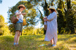 © _KUBE_ - Mother and daughter Caucasian walking in summer park holding blanket looking for a picnic spot having fun and spending quality outdoor family time together. Low angle view
